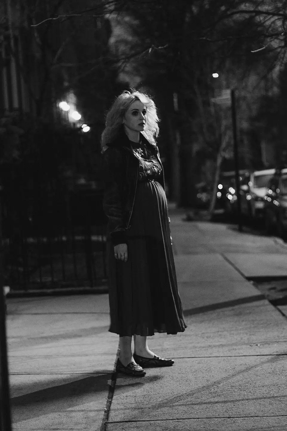night exterior, a young woman standing in the street.