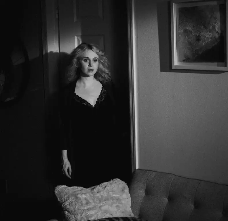 film set interior, a woman standing by a door.