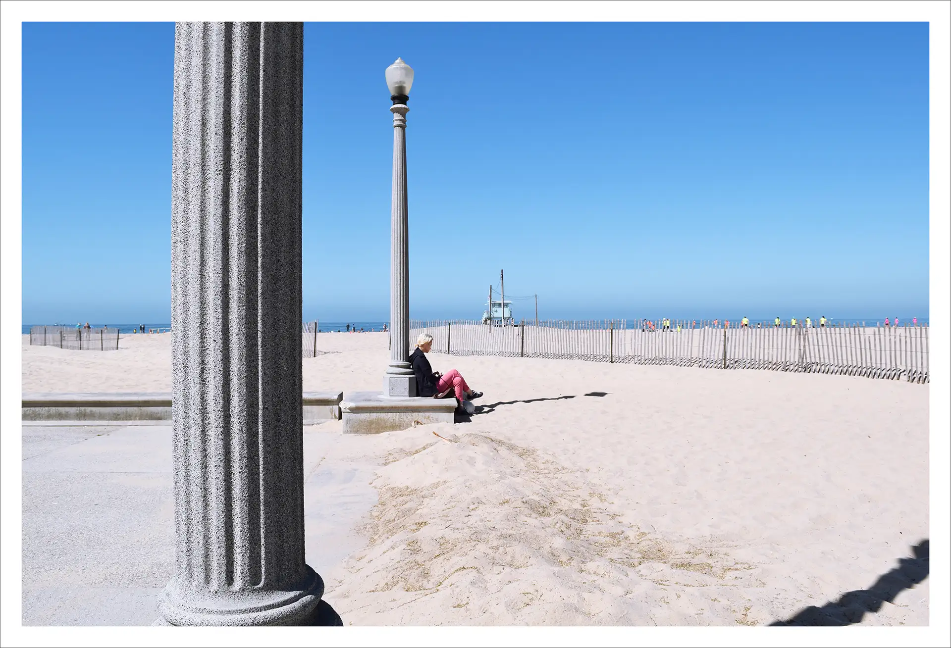 Los Angeles ,woman sitting on a concrete pillar base on the beach, sunny